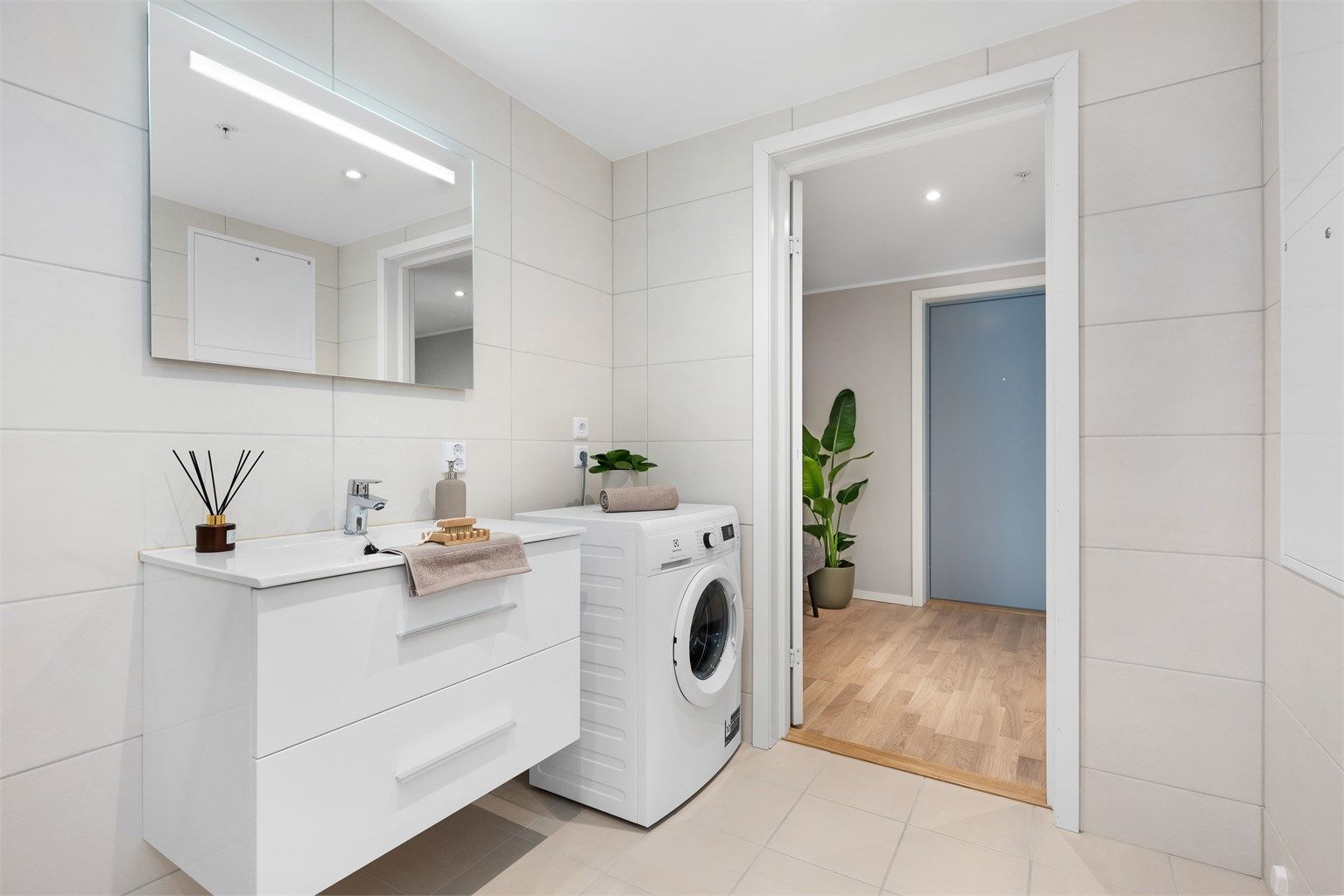 Badet har store, flotte fliser og opplegg for vaskemaskin