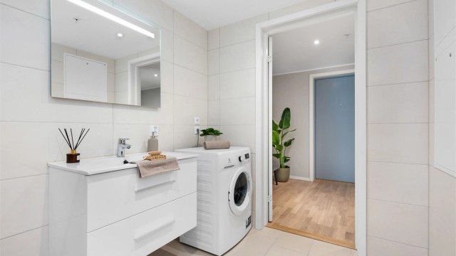 Badet har store, flotte fliser og opplegg for vaskemaskin