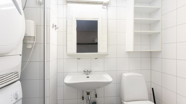Leilighetens andre bad har flislagte overflater, toalett og opplegg for vaskesøyle.