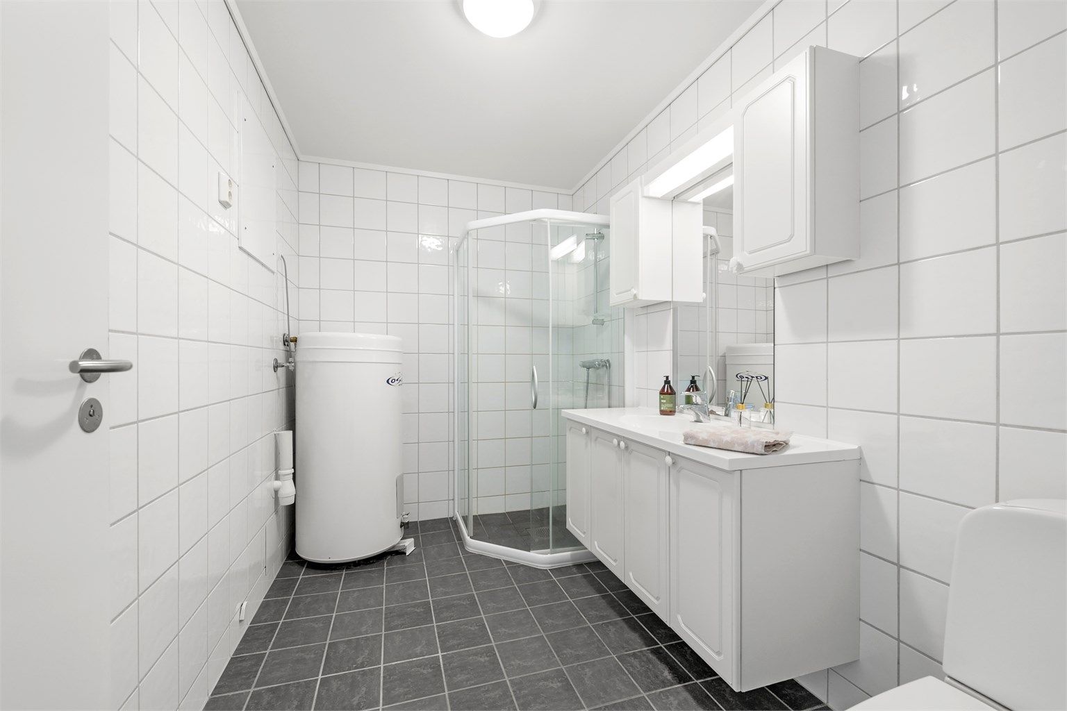 Flislagt baderom fra byggeåret med gulvvarme, dusjhjørne og opplegg for vaskemaskin.