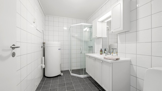 Flislagt baderom fra byggeåret med gulvvarme, dusjhjørne og opplegg for vaskemaskin.