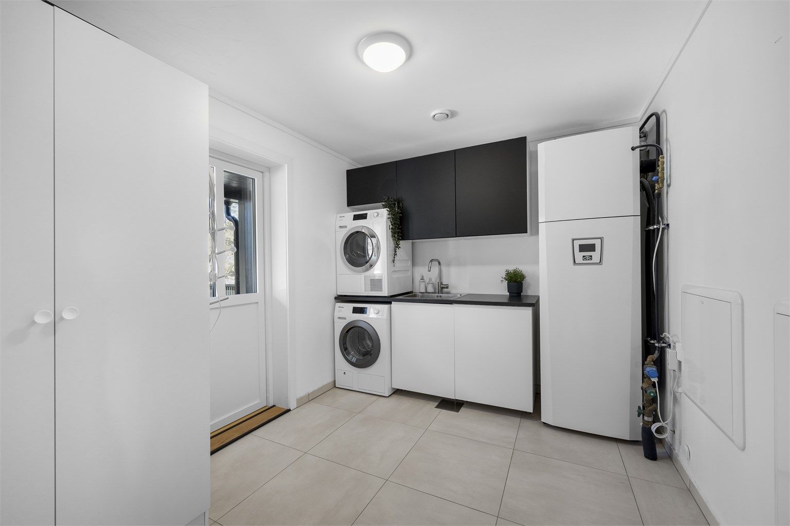 Separat vaskerom med flislagt gulv og gulvvarme. Her er også boligens tekniske anlegg samlet.