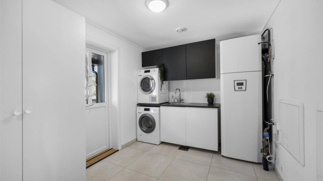 Separat vaskerom med flislagt gulv og gulvvarme. Her er også boligens tekniske anlegg samlet.