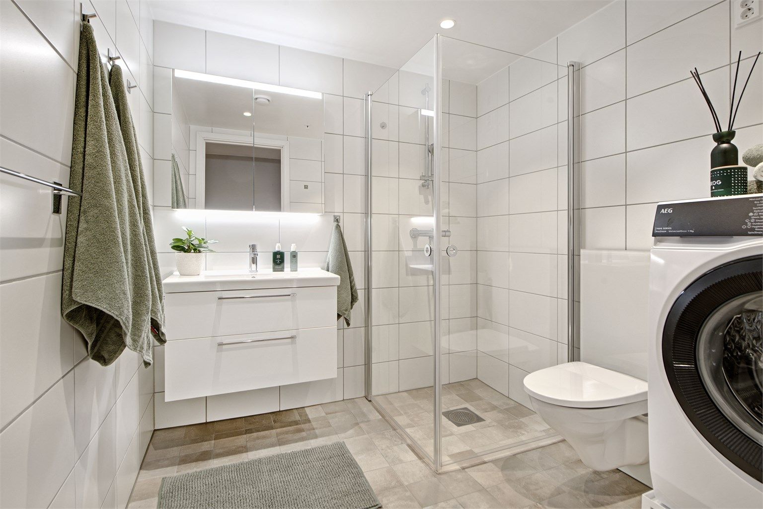 Bad - lekkert bad med flislagt gulv og vegger - gulvvarme - downlights i himling - baderomsinnredning - dusjhjørne - vegghengt toalett - opplegg for vaskemaskin 