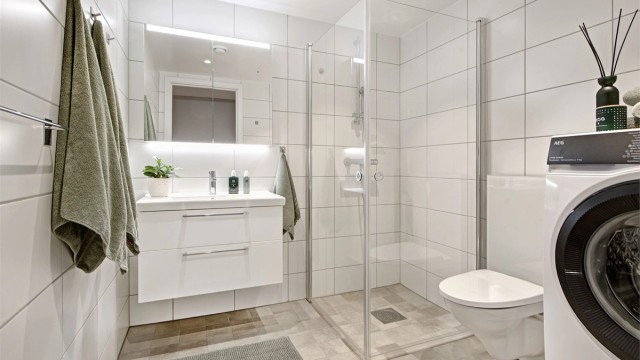 Bad - lekkert bad med flislagt gulv og vegger - gulvvarme - downlights i himling - baderomsinnredning - dusjhjørne - vegghengt toalett - opplegg for vaskemaskin