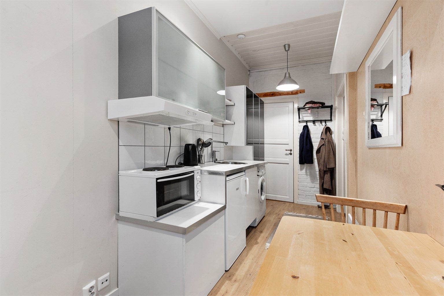 Åpen kjøkkenløsning. Innredningen er fra ukjent årstall med slette fronter. Benkeplate av laminat. Nedfelt oppvaskkum med ett-greps kjøkkenarmatur. Benkeskapsbelysning og stikkontakter over kjøkkenbenk. Frittstående kjøleskap. Ventilator i overskap.