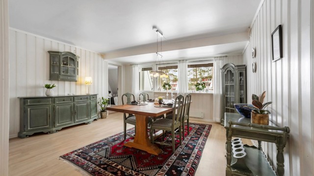 Spisestuen har lys parkett på gulvet og hvitmalt panel på veggene.