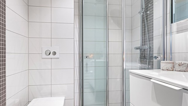 Dusjhjørne med innfellbare glassdører og vegghengt dusjarmatur med regndusj.