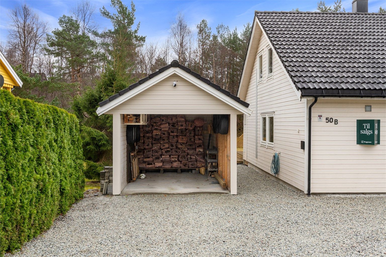 Praktisk carport med elbillader og en tilhørende bod på 5 m² for ekstra lagring.