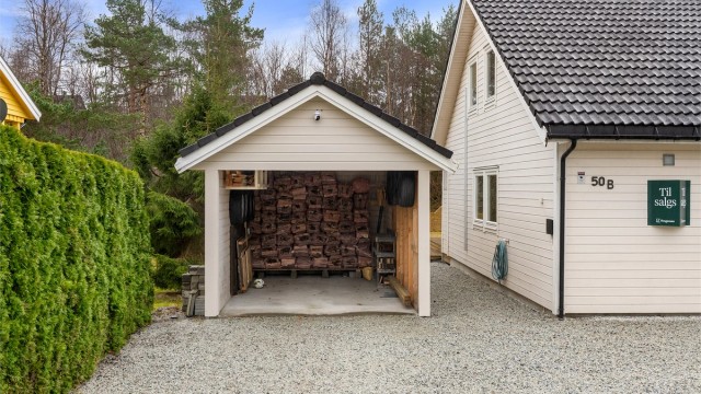Praktisk carport med elbillader og en tilhørende bod på 5 m² for ekstra lagring.