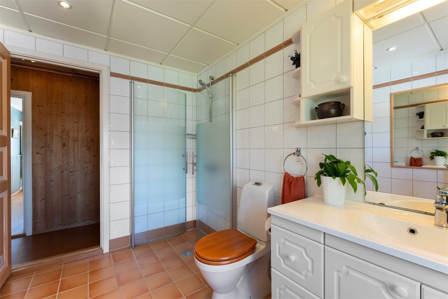 Badet er utstyrt med dusjhjørne med dører og gulvstående toalett.