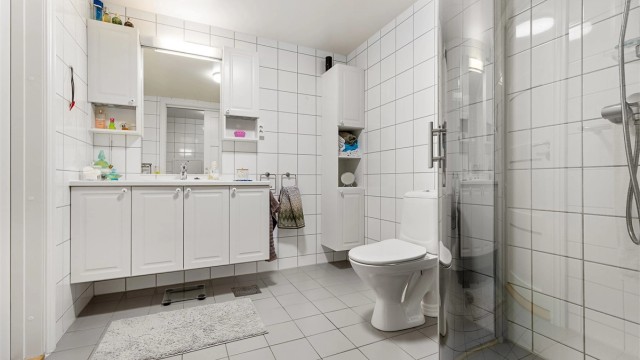 Badet er romslig og fremstår velholdt. Klassiske fargevalg på fliser skaper et tidløst baderom