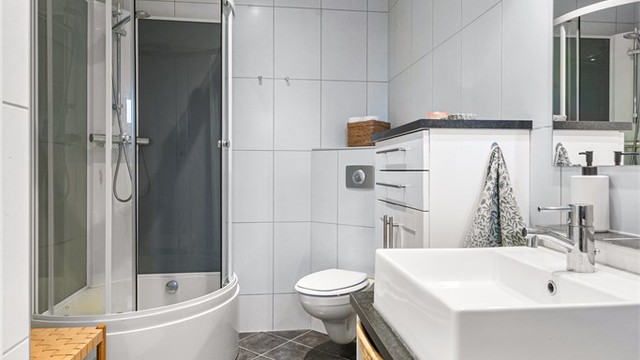 Baderomsinnredning med skuffer, ovenpåliggende servant og speil med overlys.