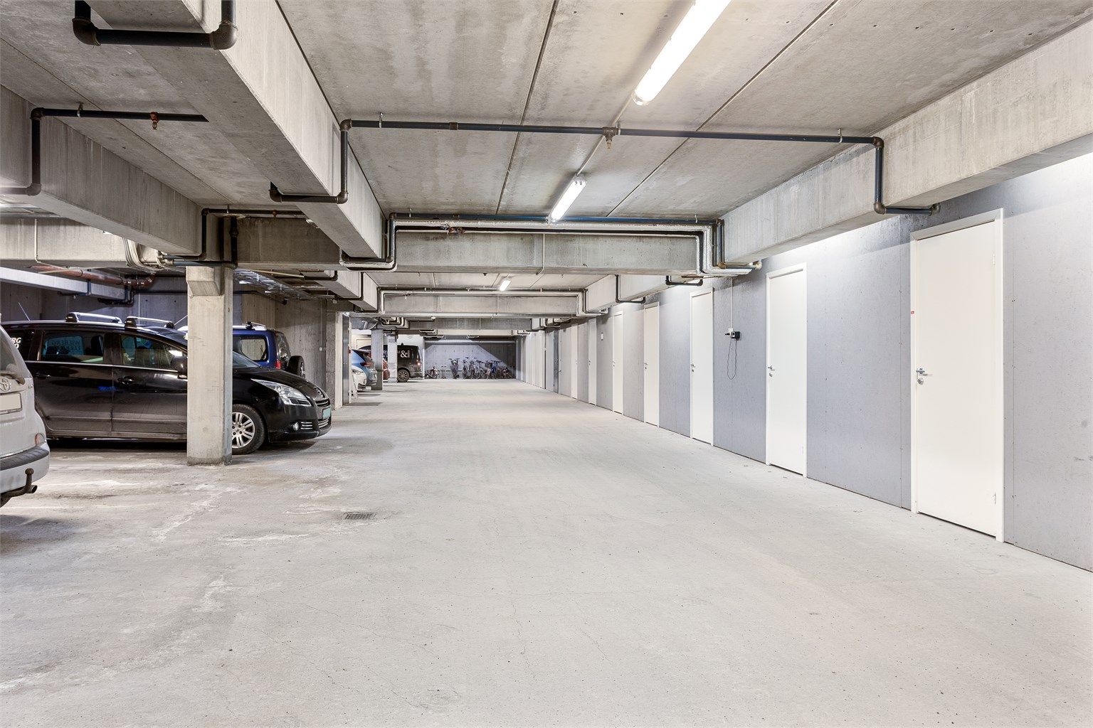 En parkeringsplass i felles garasjeanlegg. Det er montert elbillader på parkeringsplassen. Det følger med en bod rett ved p-plassen. 