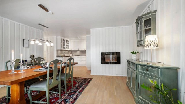 Den åpne planløsningen mellom kjøkken og spisestue skaper en praktisk overgang mellom sonene, og legger til rette for en sosial atmosfære.