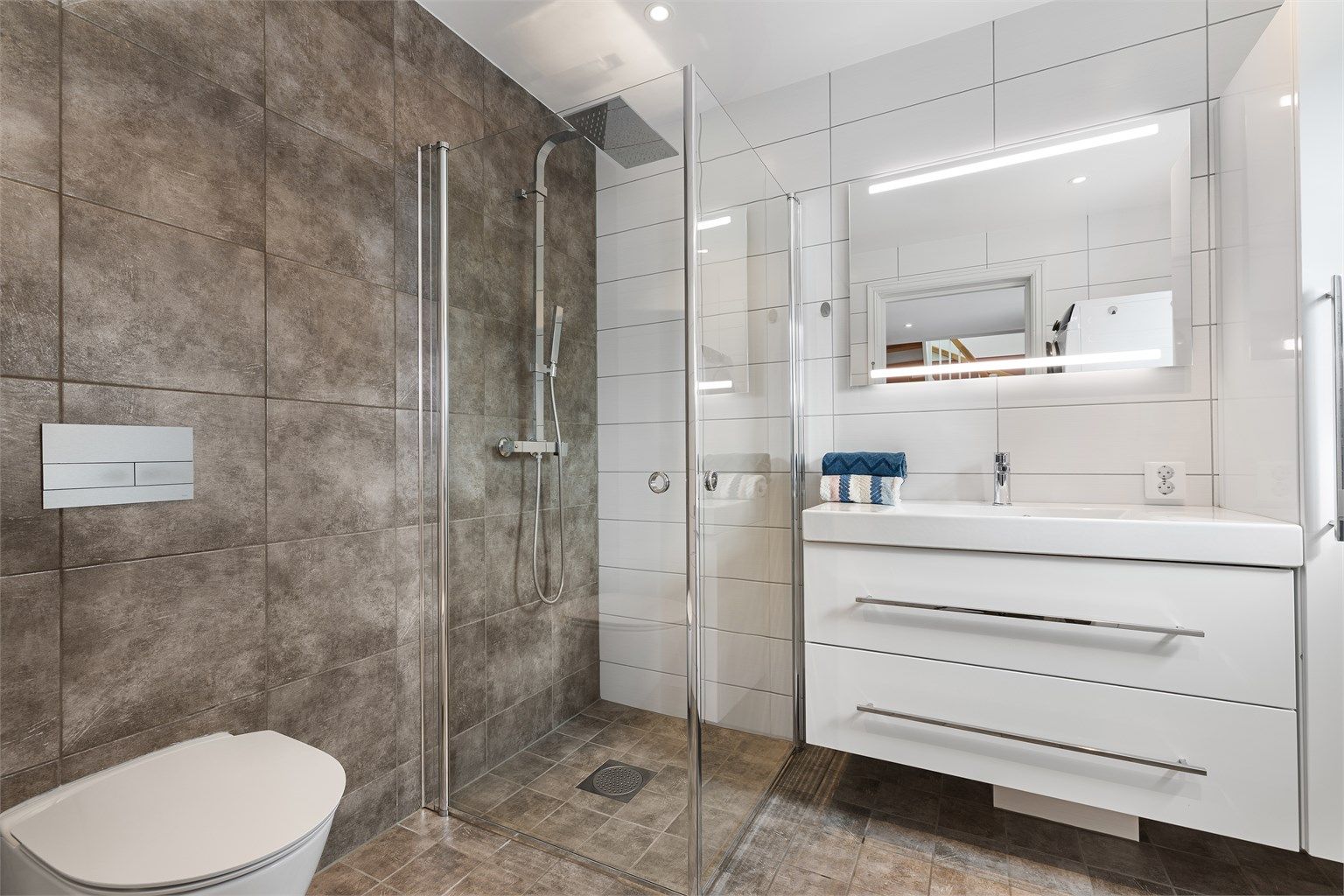 Badet i første etasje er lyst og pent med flislagte overflater og gulvvarme.