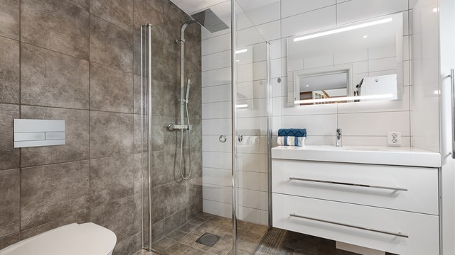 Badet i første etasje er lyst og pent med flislagte overflater og gulvvarme.