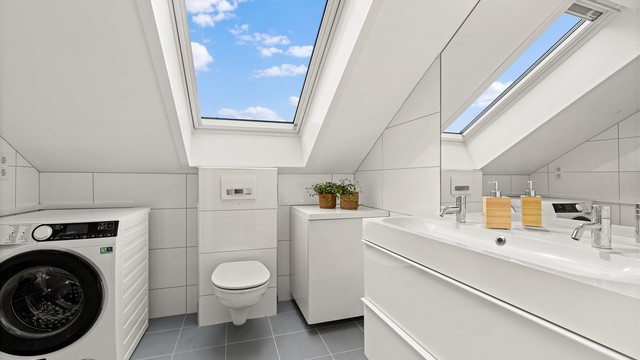 Leilighetens andre bad er romslig, med takvindu, gulvvarme og opplegg for vaskemaskin.