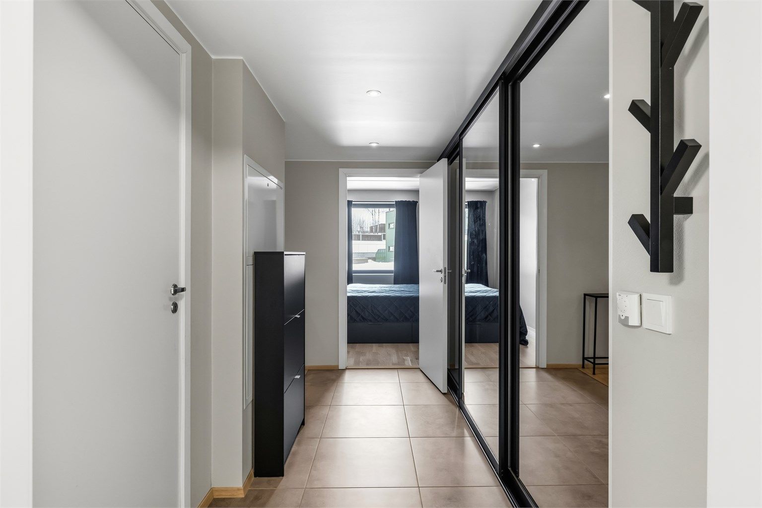 En romslig skyvedørsgarderobe med speilfronter gir rikelig med plass til yttertøy og sko.
