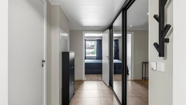 En romslig skyvedørsgarderobe med speilfronter gir rikelig med plass til yttertøy og sko.