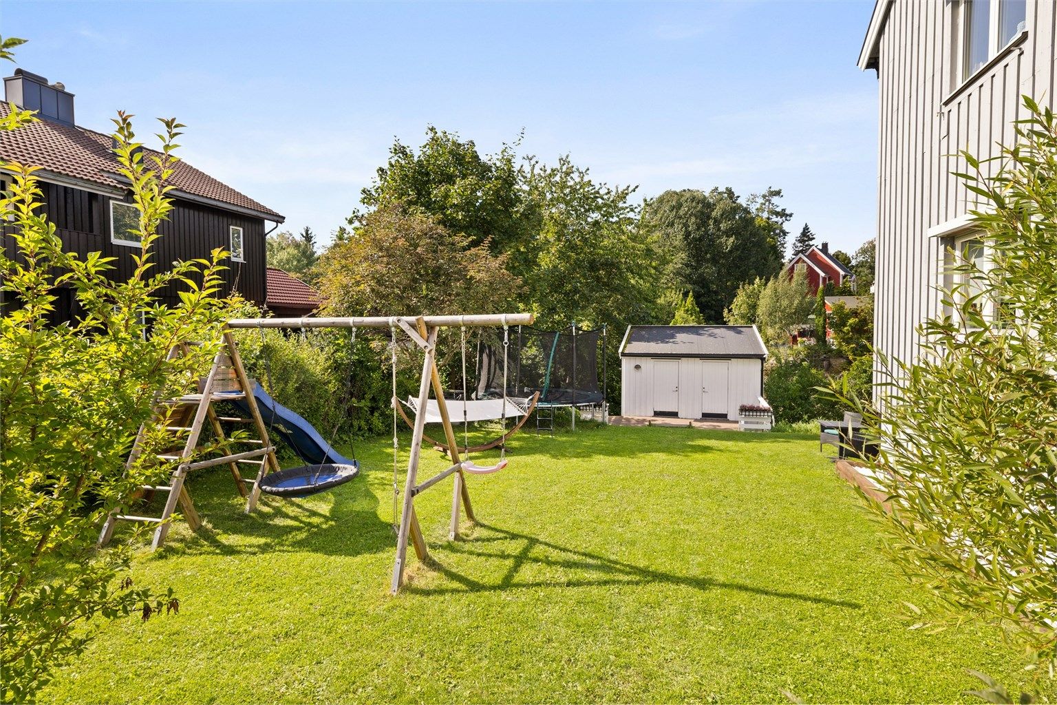 Stor felles hage. Hagen er pent opparbeidet med gressplen, prydbusker, trær og hekk, og det er rikelig med boltreplass for store og små.