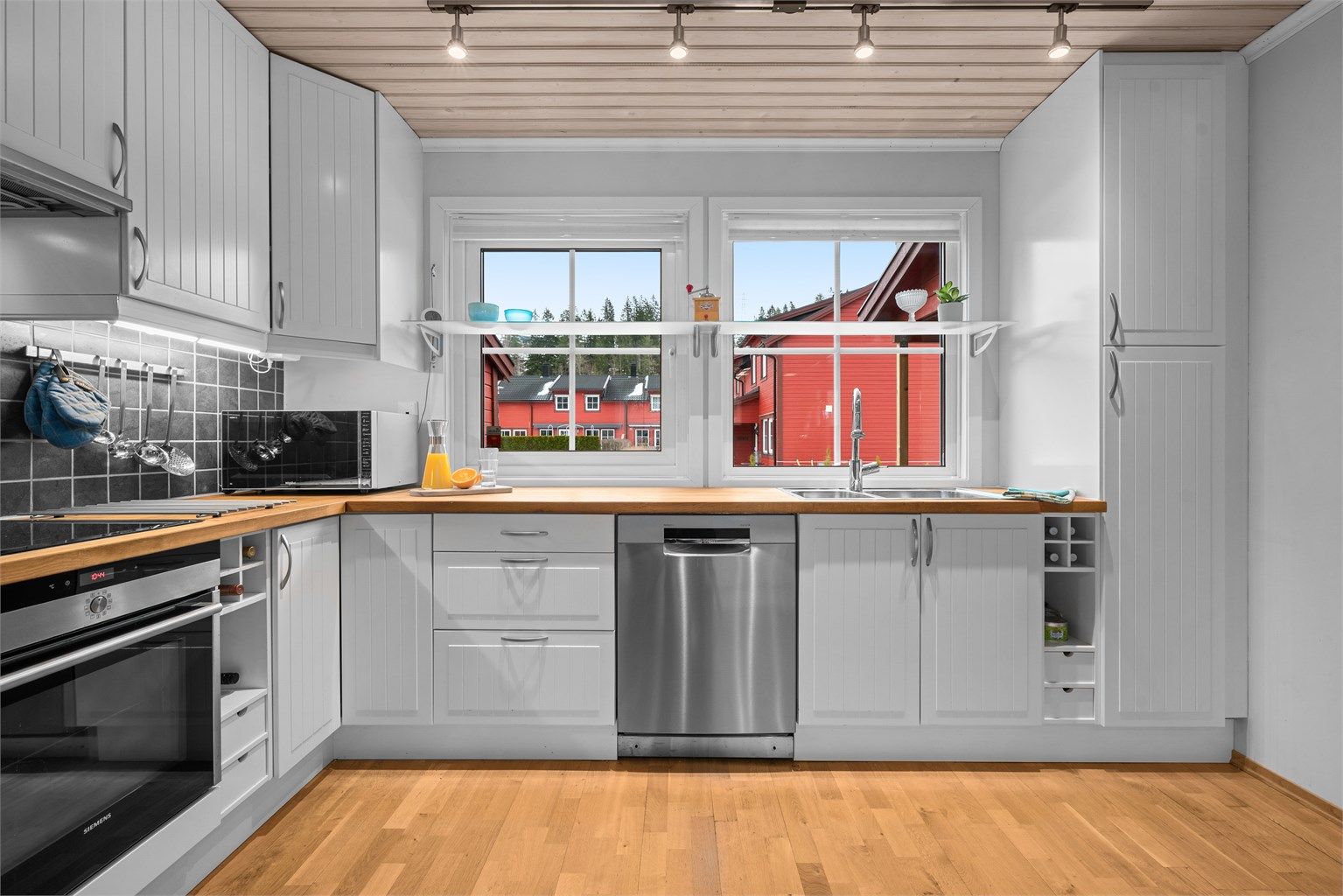 Kjøkkenet er utstyrt med rikelig skapplass og smarte oppbevaringsløsninger, inkludert vinhyller.