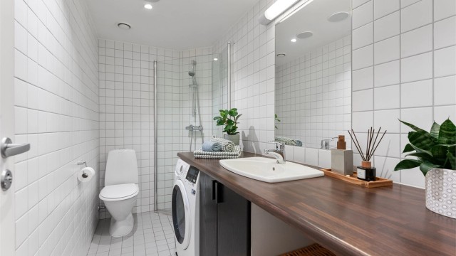 Badet er utstyrt med dusjhjørne med dører, toalett og servantinnredning.