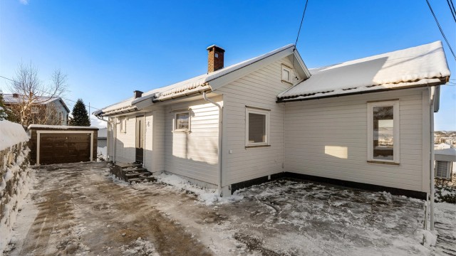 Fasade med god plass til parkering m.m. Det er også lagt opp til fremtidig el-bil lader ved husveggen.