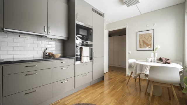 Moderne kvalitetskjøkken med integrerte hvitevarer og hyggelig spiseplass ved vinduet.