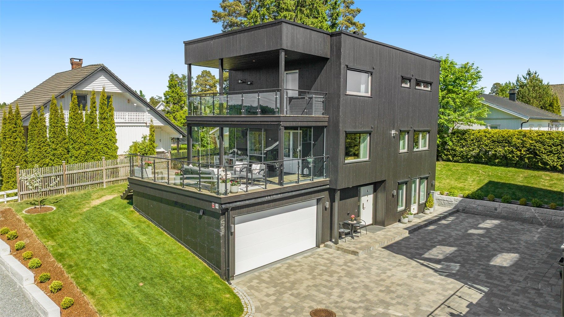 Fasaden har stående bordkledning og et moderne uttrykk med store vindusflater.