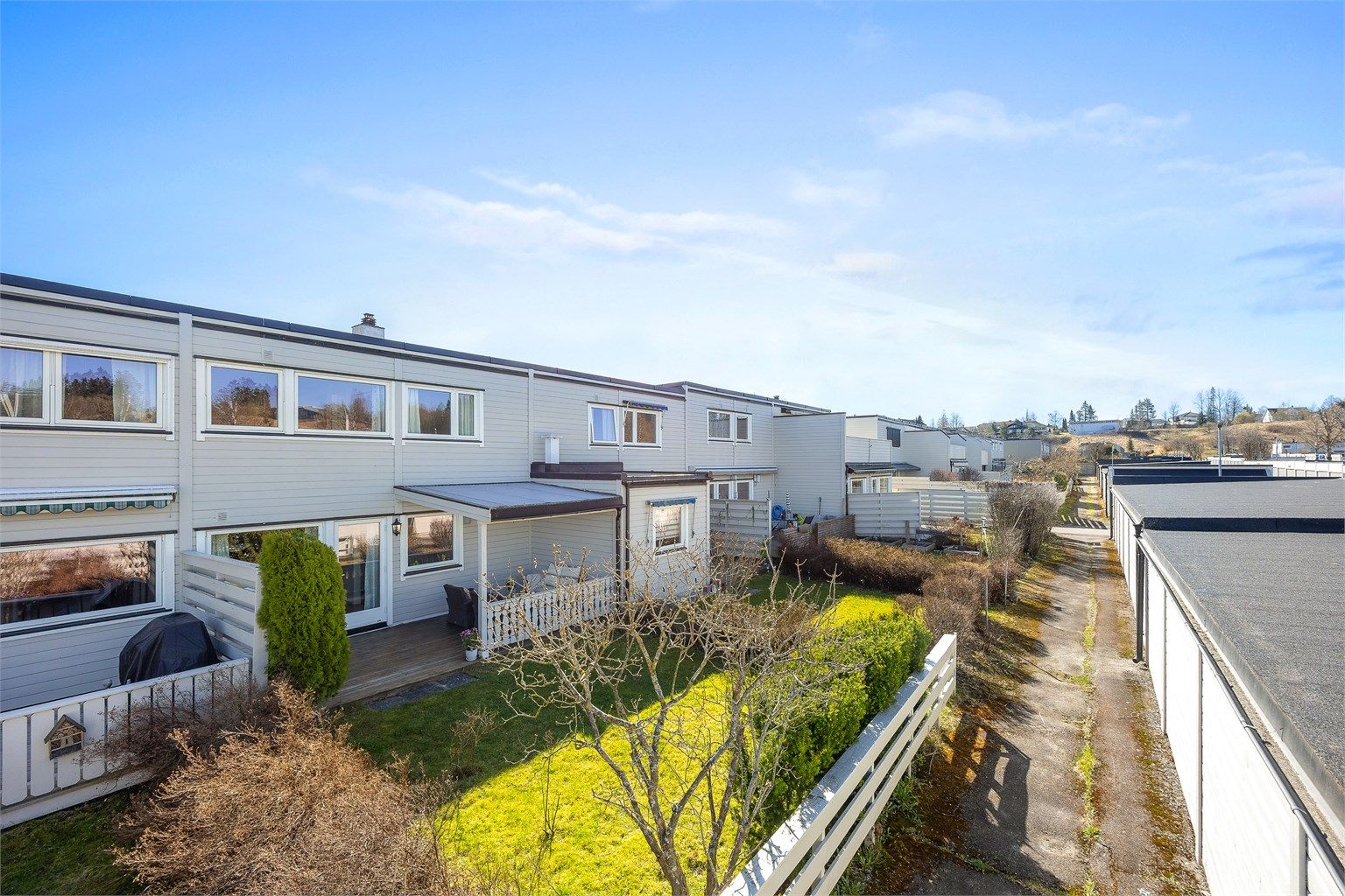 Oversikt over baksiden av boligrekken, med private hager og terrasser.