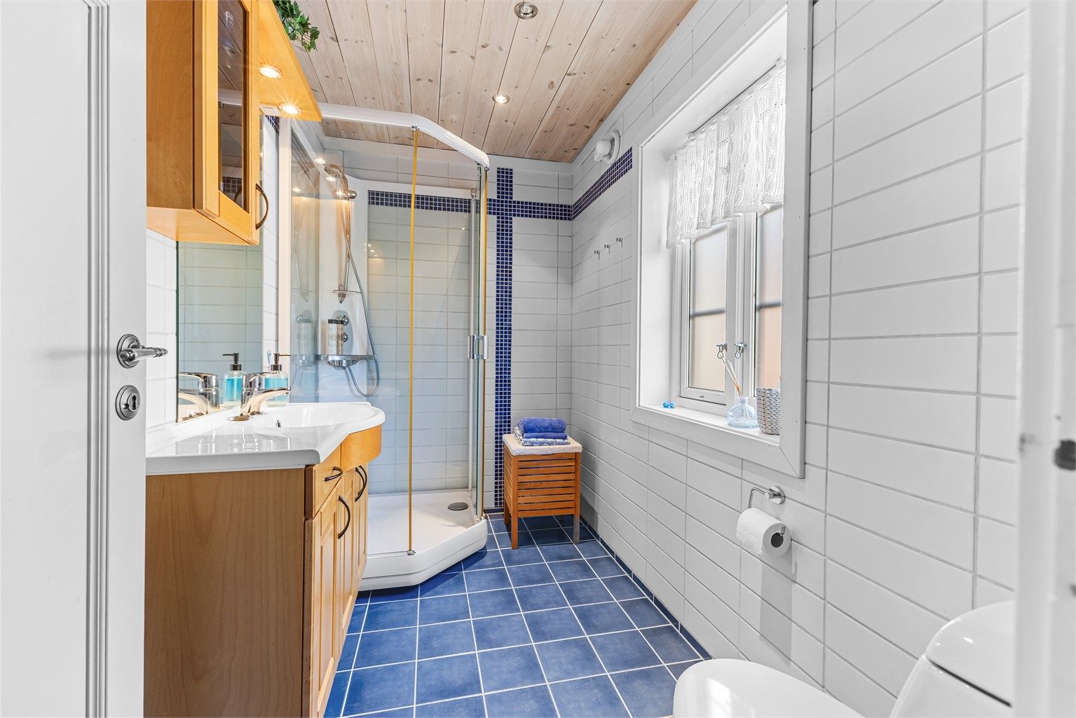 Flislagt bad med dusjkabinett, toalett, servant i innredning og varmekabler i gulv