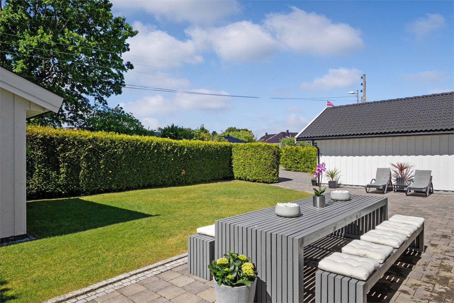 Tomten er pent opparbeidet med velstelte plenarealer, rammet inn av tettvokst og velfrisert hekk. 