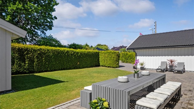 Tomten er pent opparbeidet med velstelte plenarealer, rammet inn av tettvokst og velfrisert hekk.