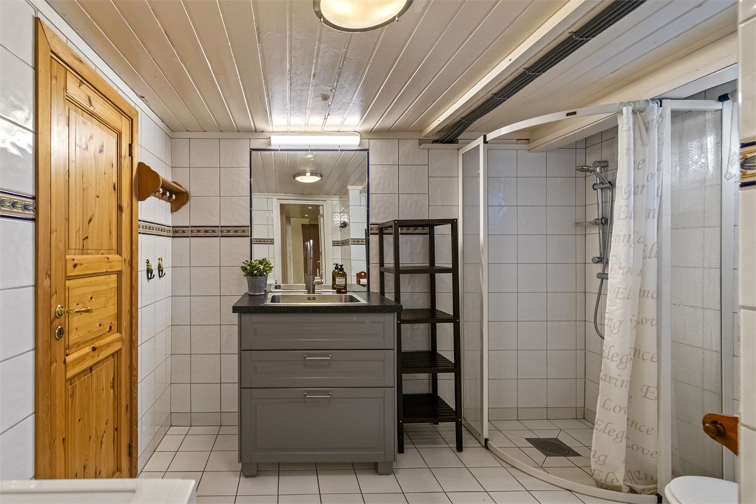 Badet er utstyrt med dusjhjørne, toalett og servant.