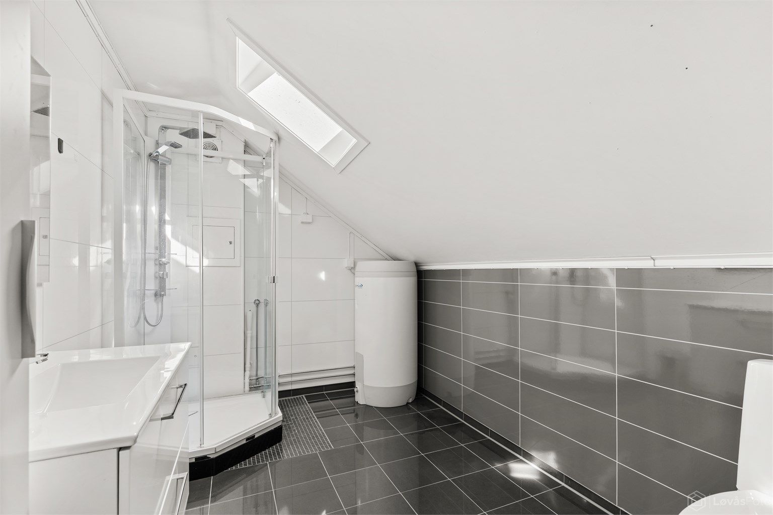 Badet i andre etasje har flislagt gulv med varme, takvindu og dusjkabinett.