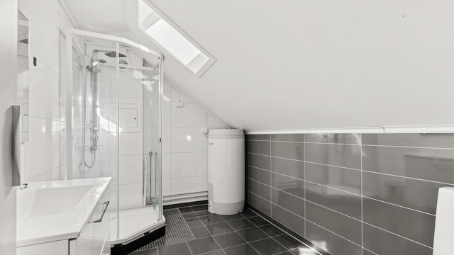 Badet i andre etasje har flislagt gulv med varme, takvindu og dusjkabinett.
