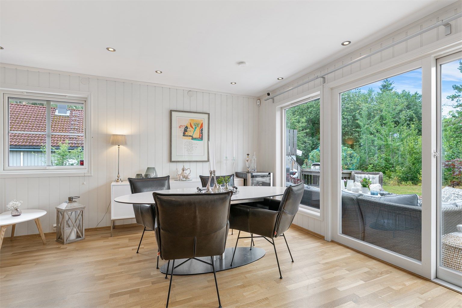 Utgang til hagen og store vindusflater mot grønne omgivelser.

