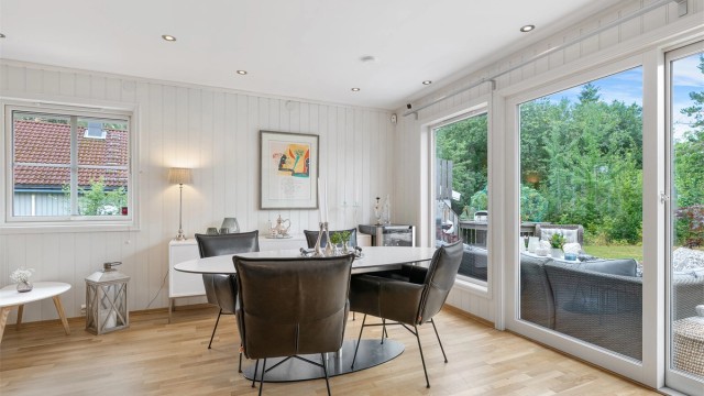 Utgang til hagen og store vindusflater mot grønne omgivelser.