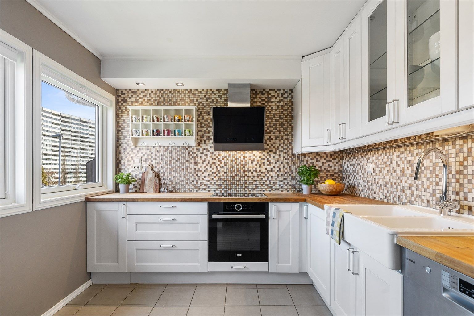 Kjøkkenet har en tidløs innredning med profilerte fronter, benkeplate i tre og fliser over benken.