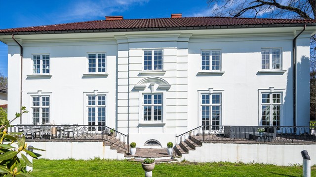Den klassiske fasaden er velholdt, med trevinduer og delikat utforming.