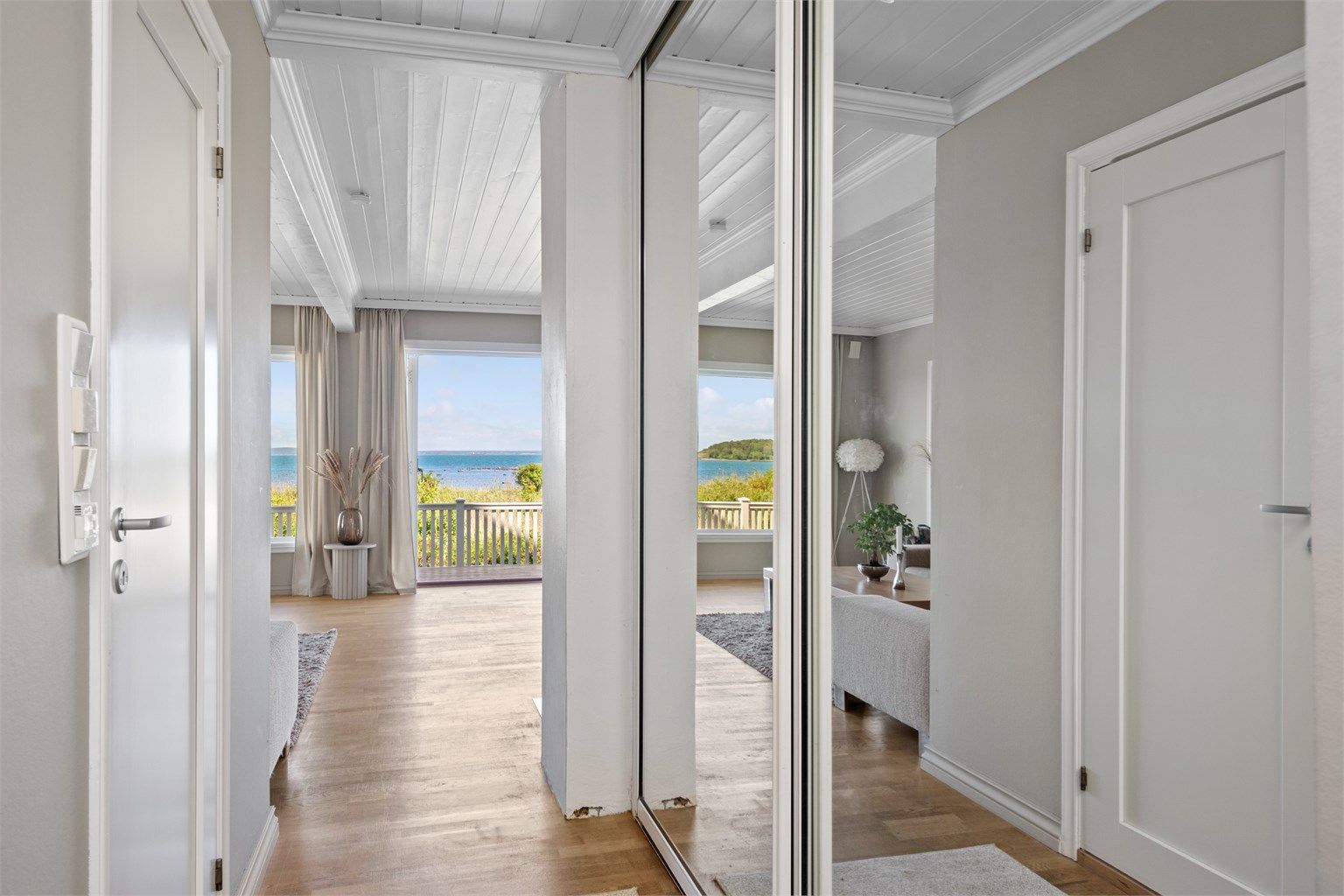 Entreen ligger åpen mot stuen, slik at det første man ser er den nydelige sjøutsikten via store stuevinduer. Entreen har også en stor skyvedørsgarderobe med speilfronter langs den ene siden og inngang til badet på den andre.