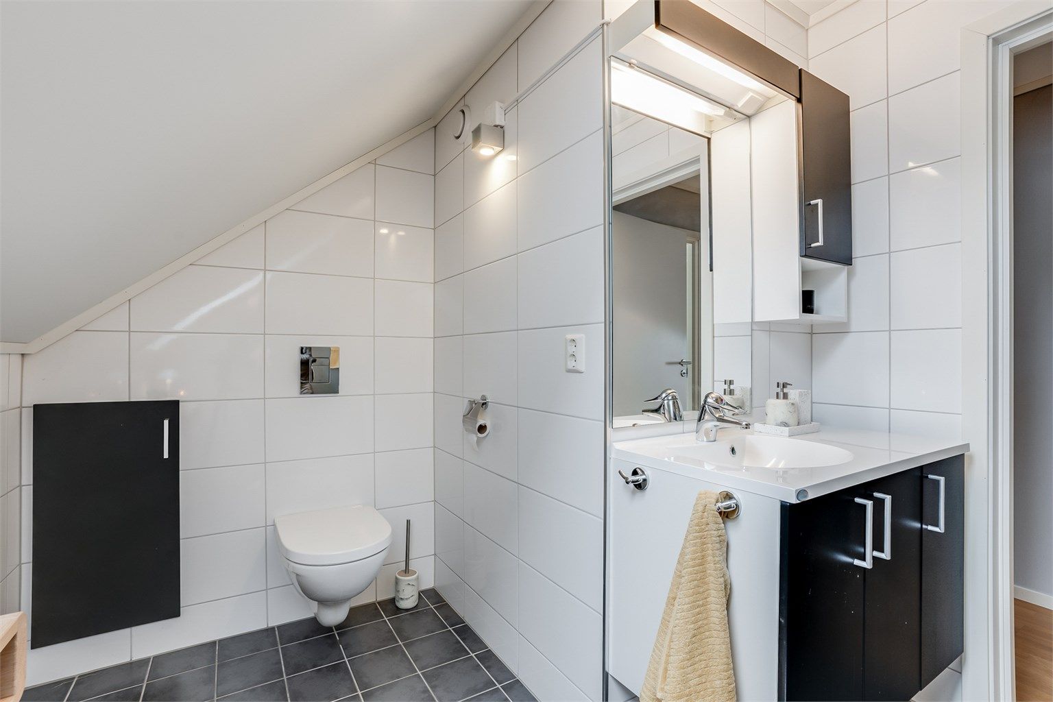 Bad på loft har innredning fra Fossbad. Vegghengt toalett. Dusjnisje med glassdør