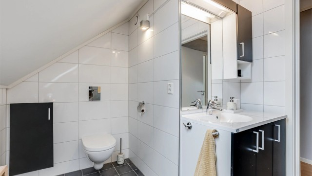 Bad på loft har innredning fra Fossbad. Vegghengt toalett. Dusjnisje med glassdør