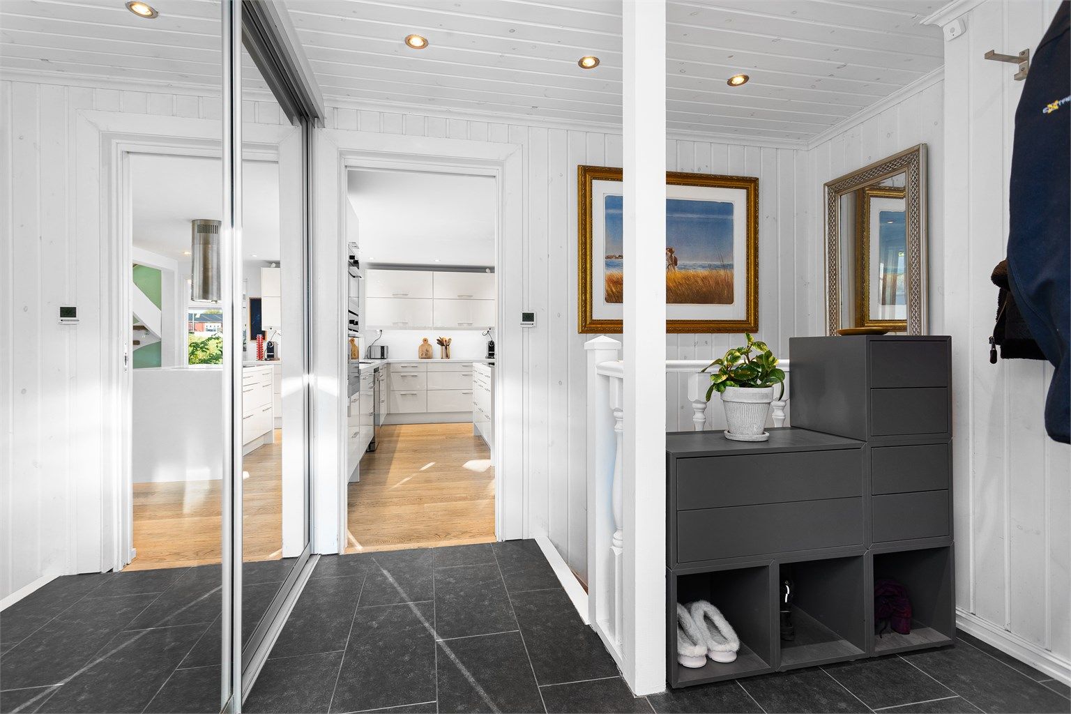 Entréen har flislagt gulv med varme, downlights i taket og skyvedørsgarderobe med speil.