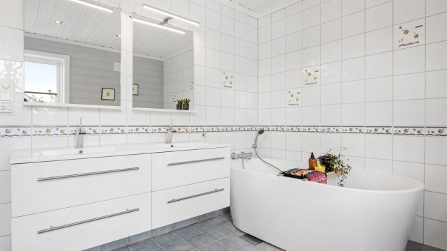 Badet i første etasje har badekar, gulvvarme og innredning med to servanter.
