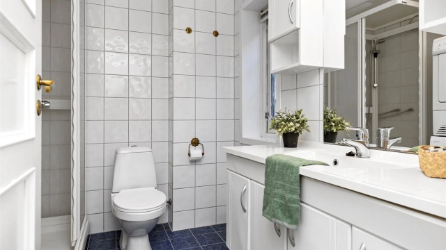 Flislagt bad i kjellerdelen med dusjkabinett, toalett og servant.