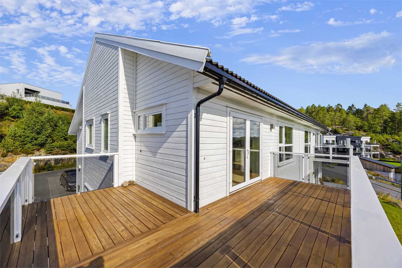 Veranda med glassrekkverk og god plass til sittegruppe, samt grill.