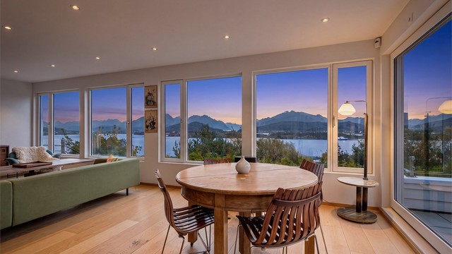 Kveldsstemning i stuen med opplyst himling og utsikt mot skumringen over fjorden.