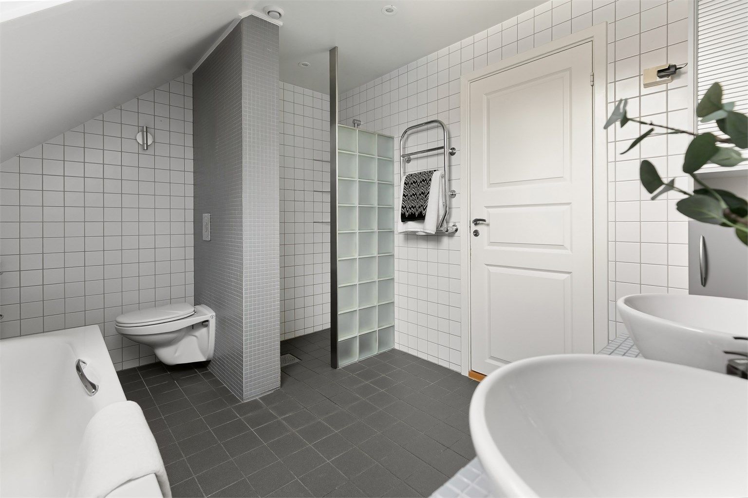 Badet har både badekar og en separat dusjnisje med vegg av glassbyggerstein.